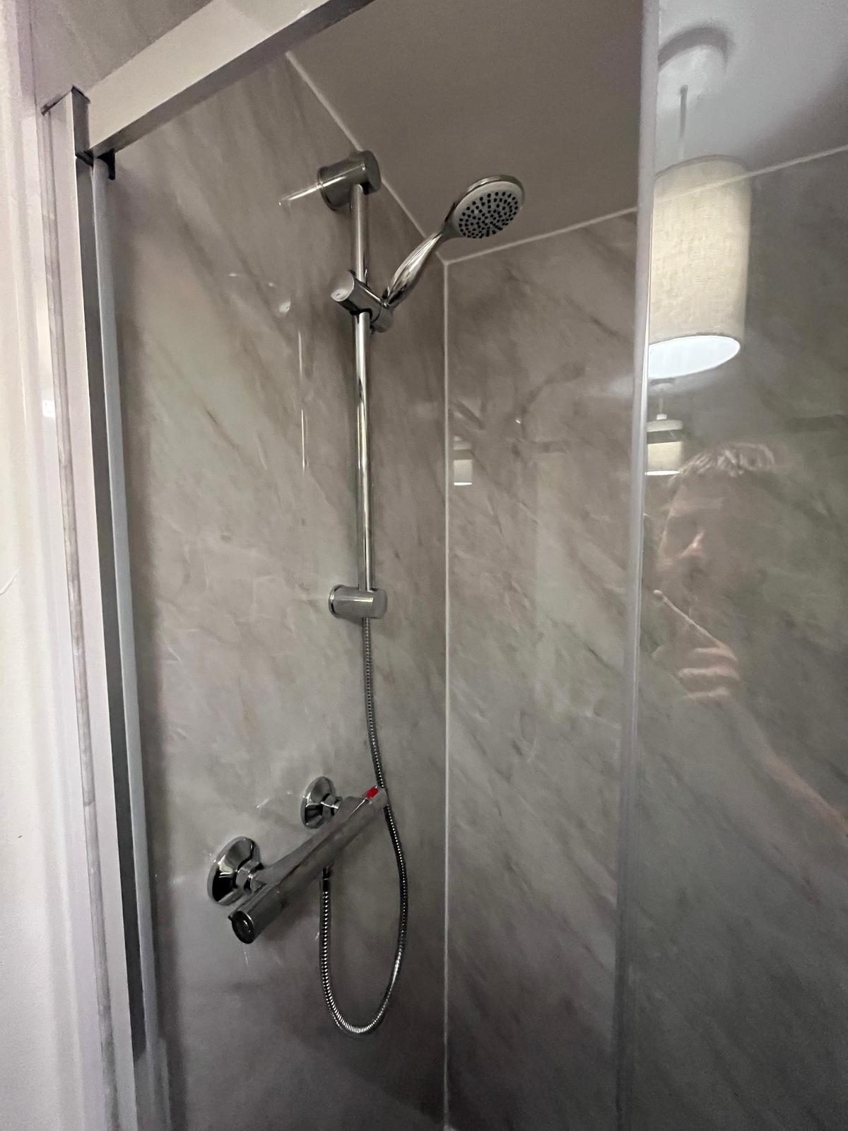 Thermostatic shower valve and riser rail fitted on marble-effect shower panels
