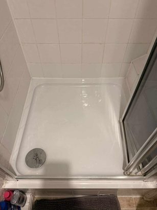 Old shower tray in a tiled cubicle before a new shower installation