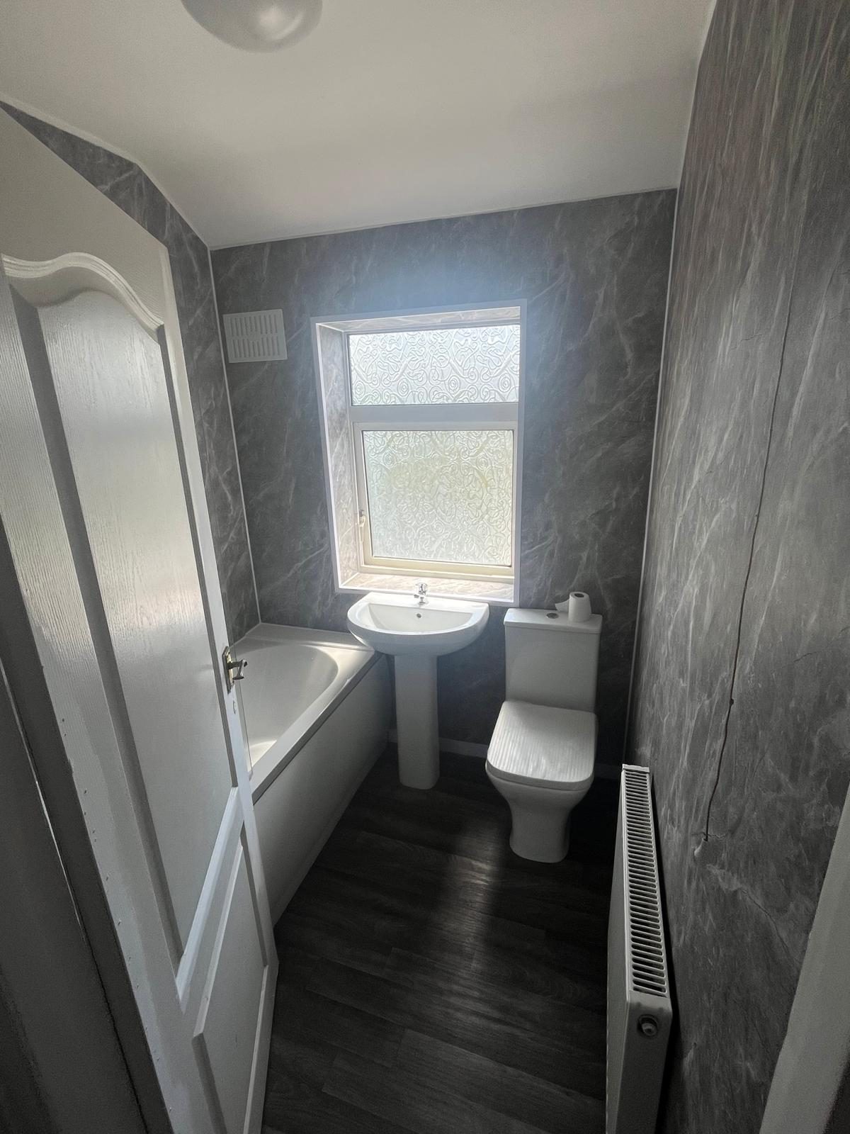 Renovated compact bathroom with dark wall tiles, white bath and toilet fitted in Lytham St Anne's