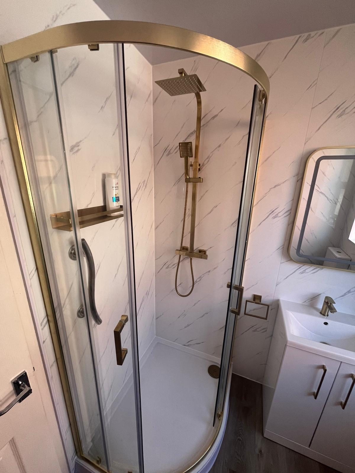 Quadrant shower enclosure with gold frame and vanity basin unit installed