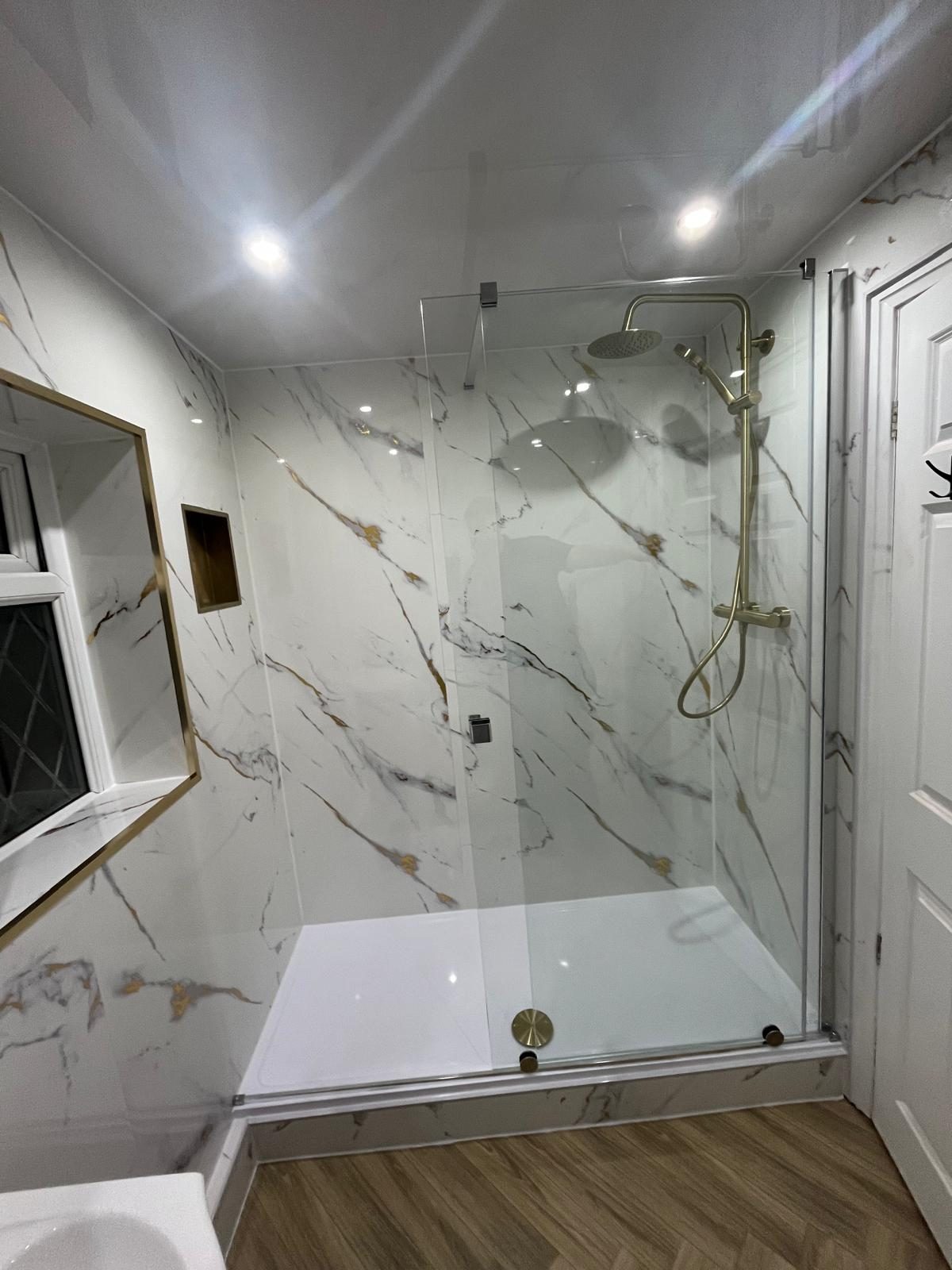 Large walk-in shower installation with glass screen and gold rainfall shower set