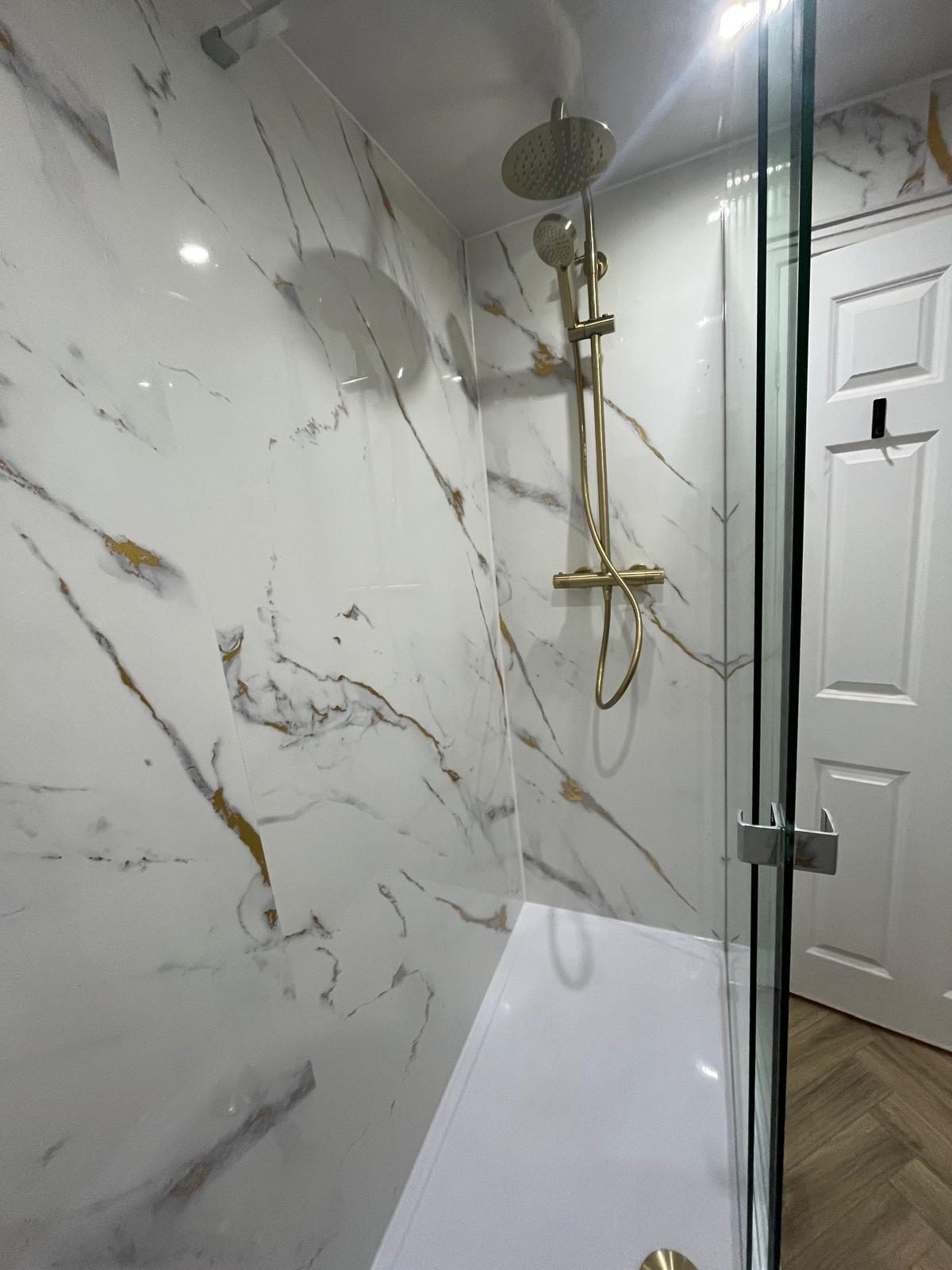 Walk-in shower installation with marble-effect panels and brushed gold rainfall shower