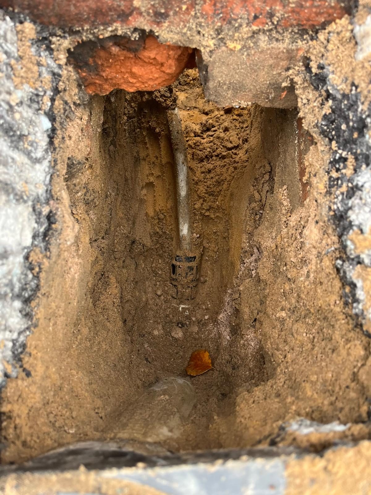 Underground pipework exposed during leak detection and repair beneath a wall