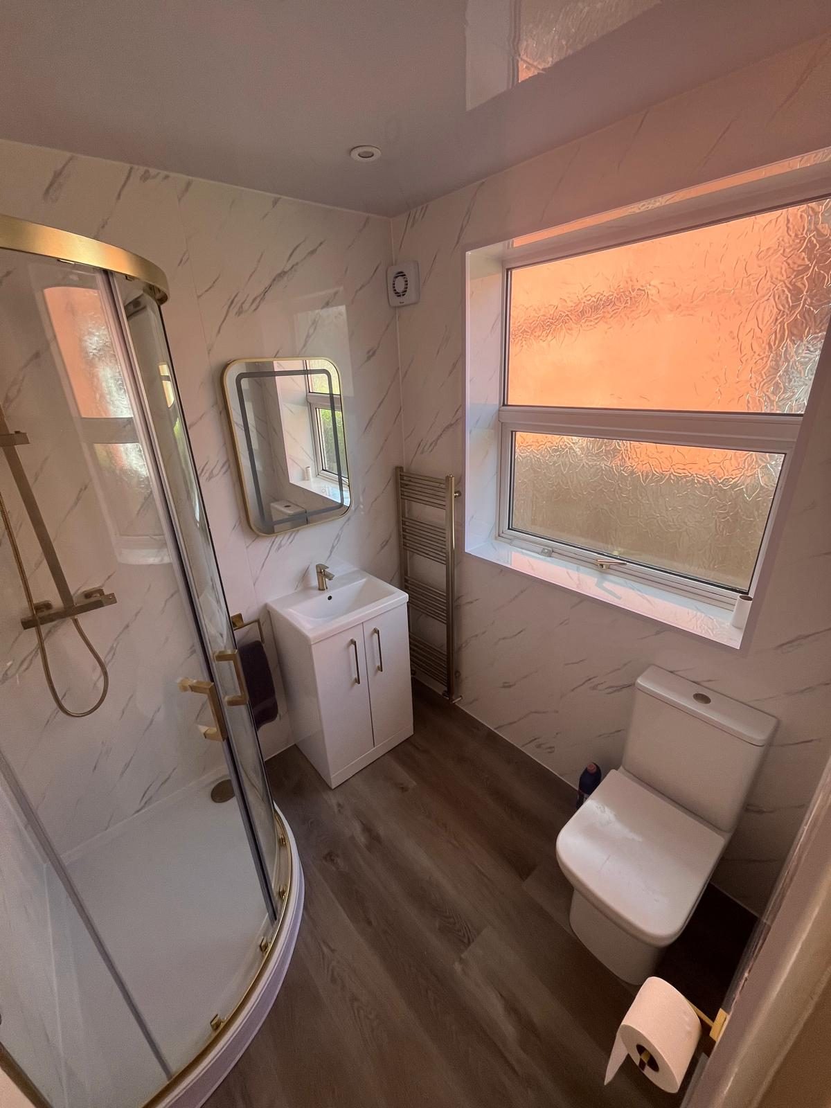 Completed bathroom renovation with quadrant shower enclosure, vanity unit and wood-effect flooring in Lytham St Anne's