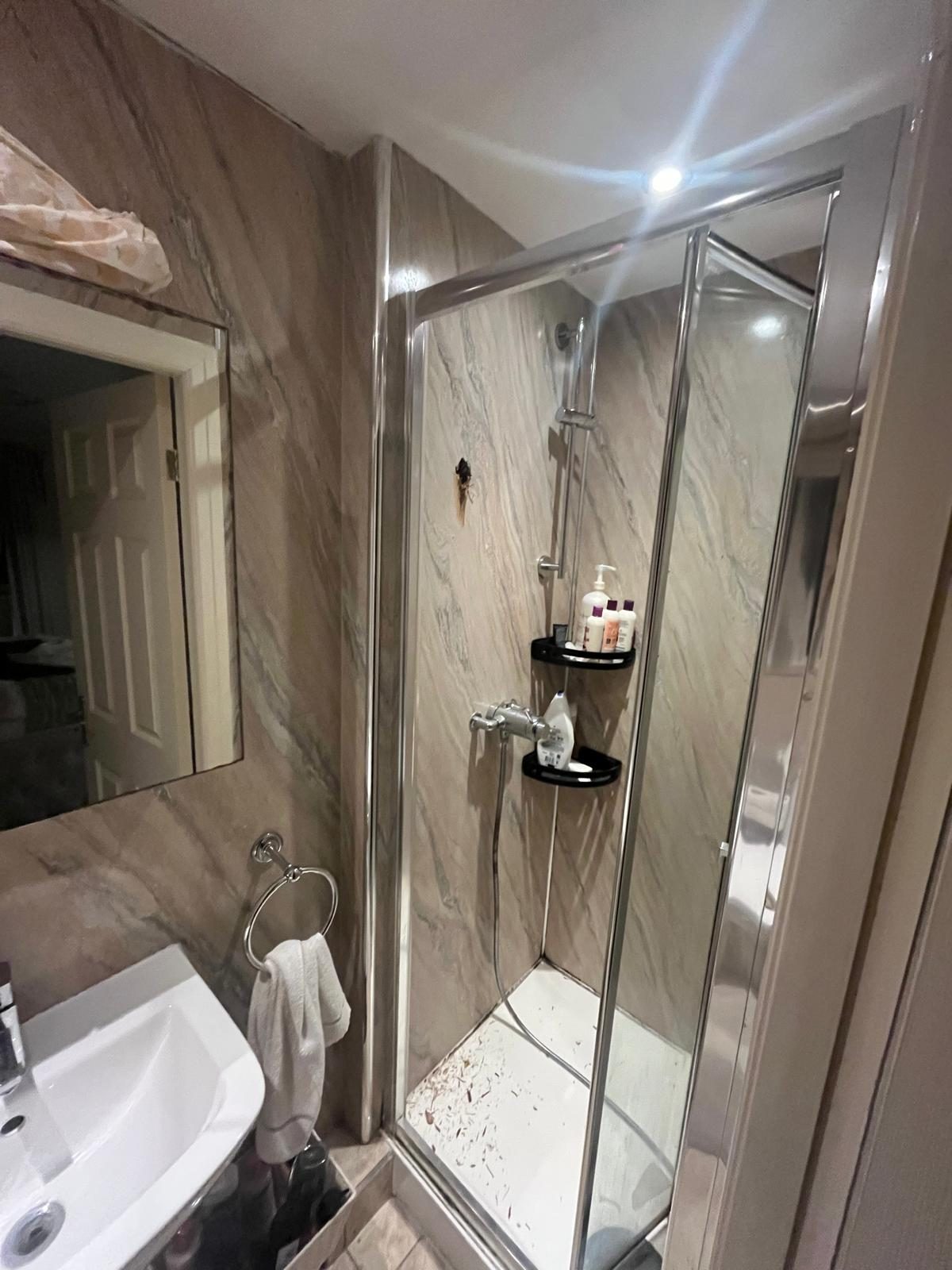 New bathroom with shower enclosure, marble-effect wall panels, toilet and basin