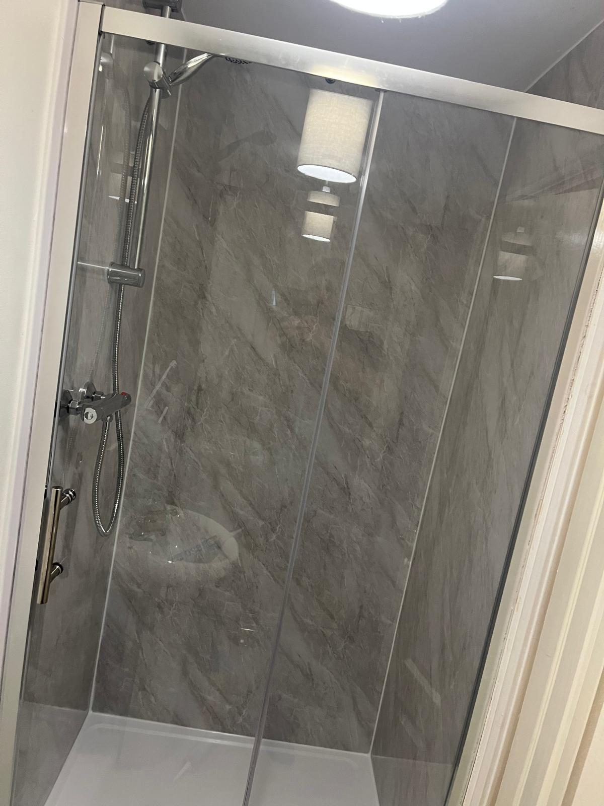 Sliding door shower enclosure fitted with grey marble-effect wall panels