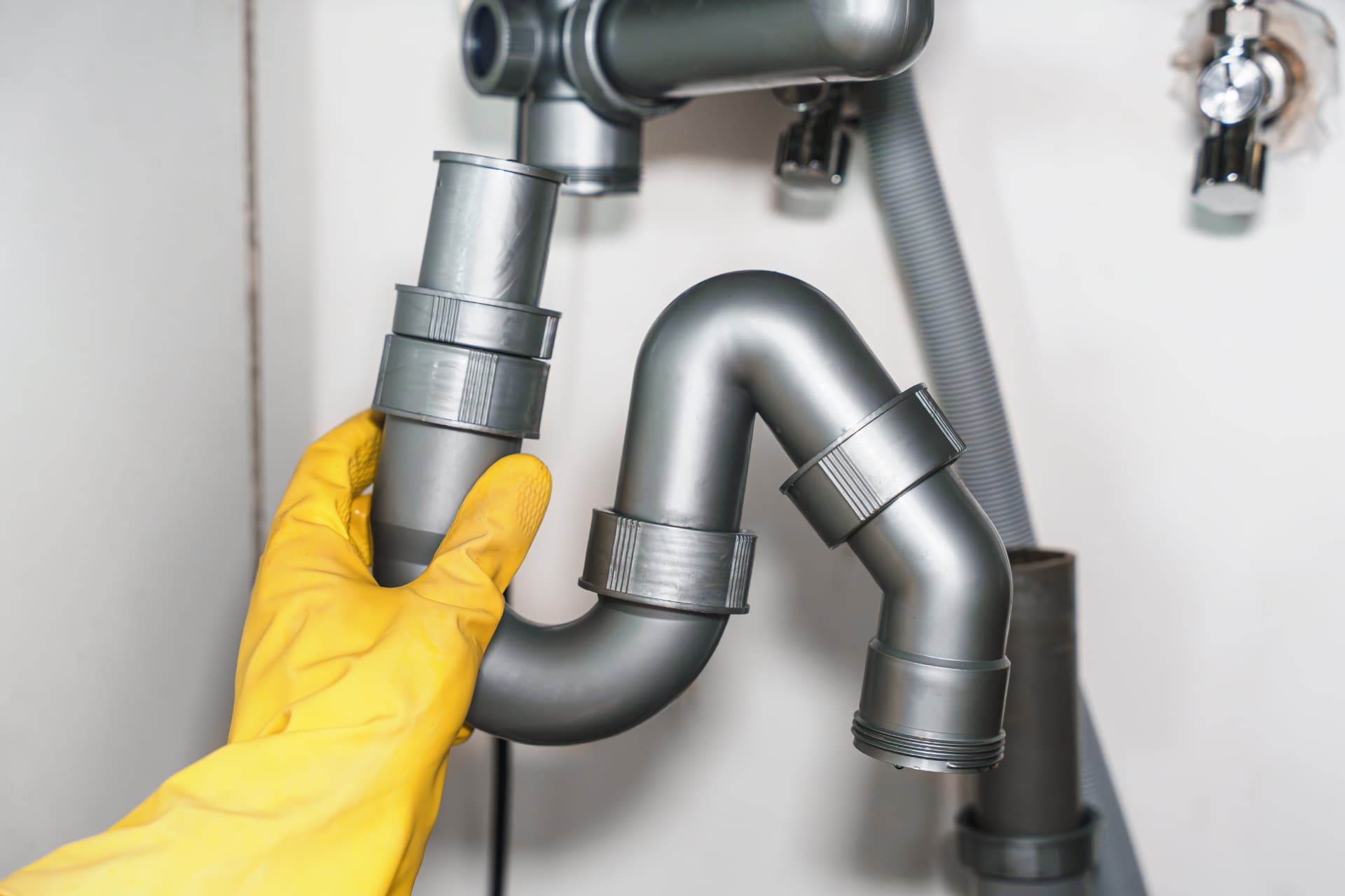 Plumber refitting a sink waste trap during a blocked drainage repair