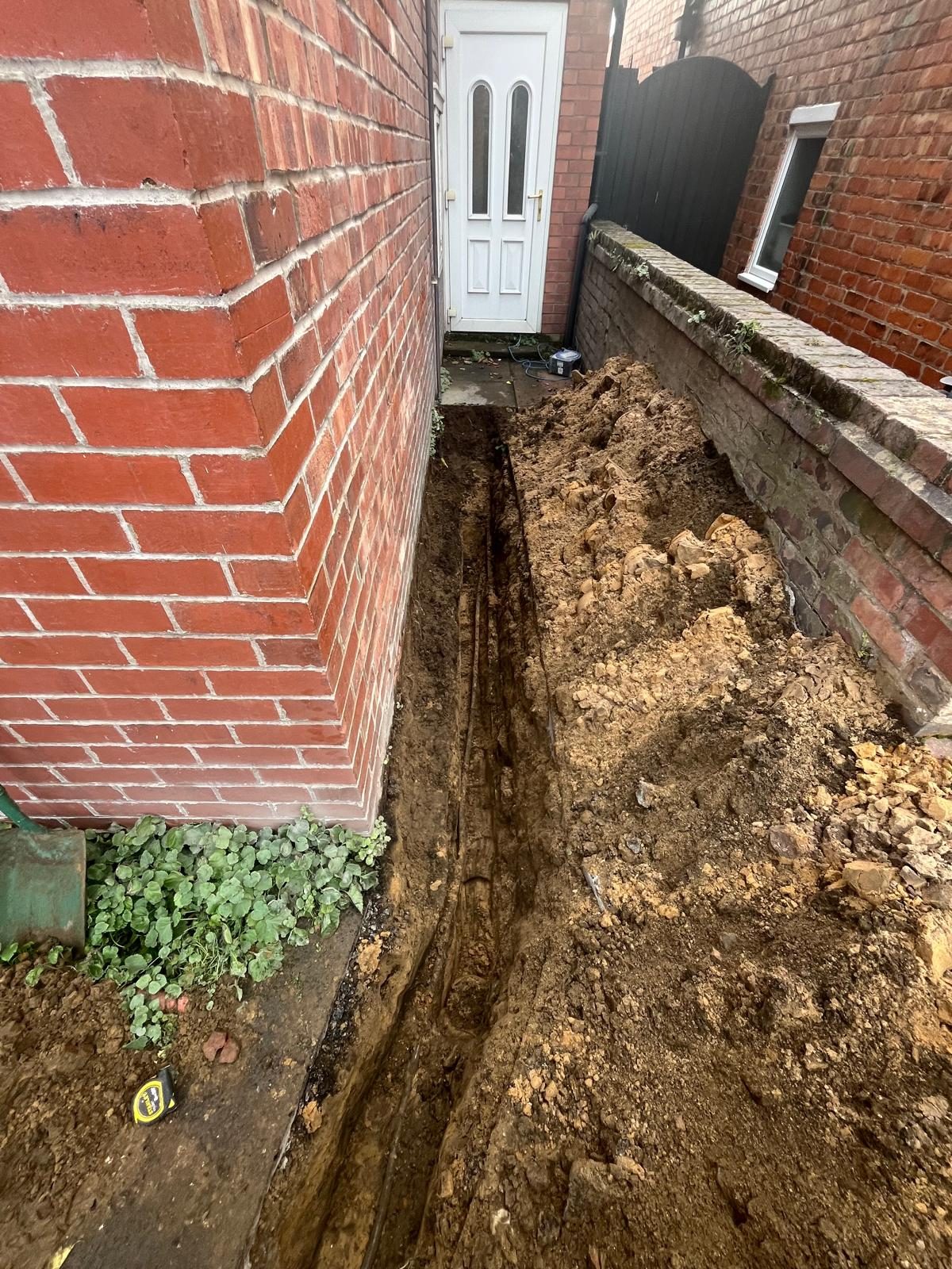 Excavated trench tracing an underground water leak to the rear of a property